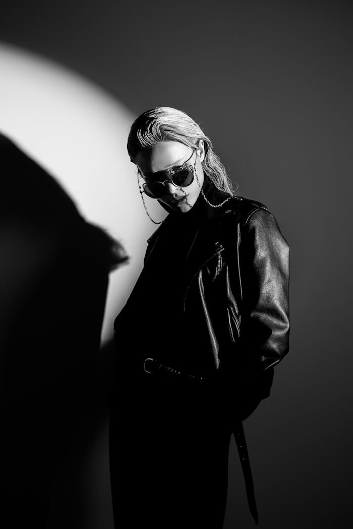Striking black-and-white portrait of a woman wearing a leather jacket and sunglasses.